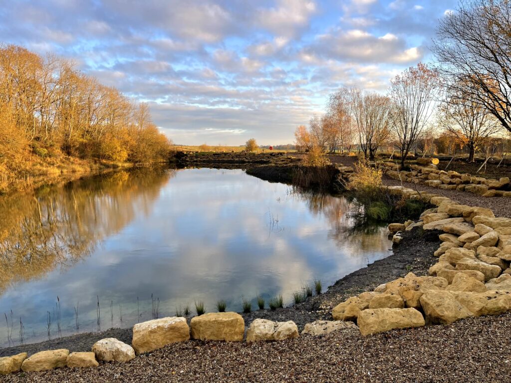 One of the fishing lakes at Rockingham Forest Park, with stone-edged swims along the near bank and the far bank reflected in still water