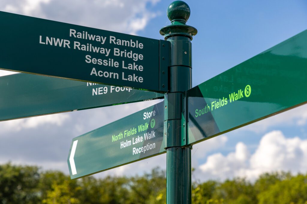 A green fingerpost on the park pointing to the walks