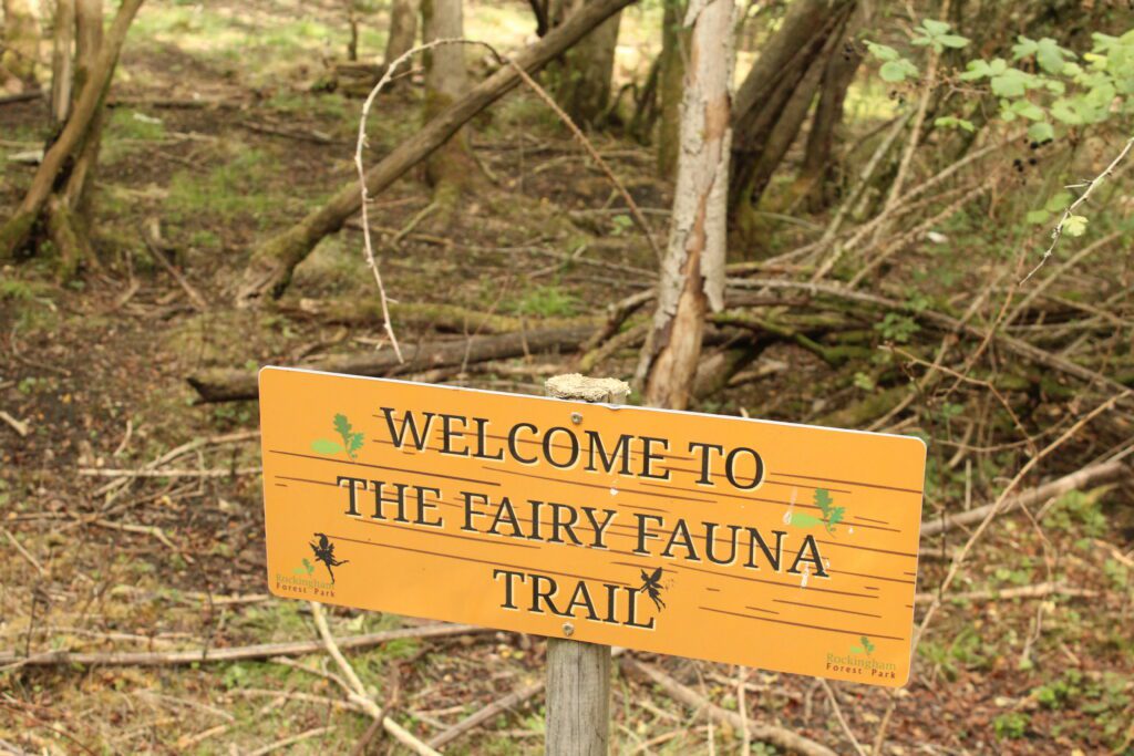 The carved Welcome to the Fairy Fauna Trail sign in the woods at Rockingham Forest Park