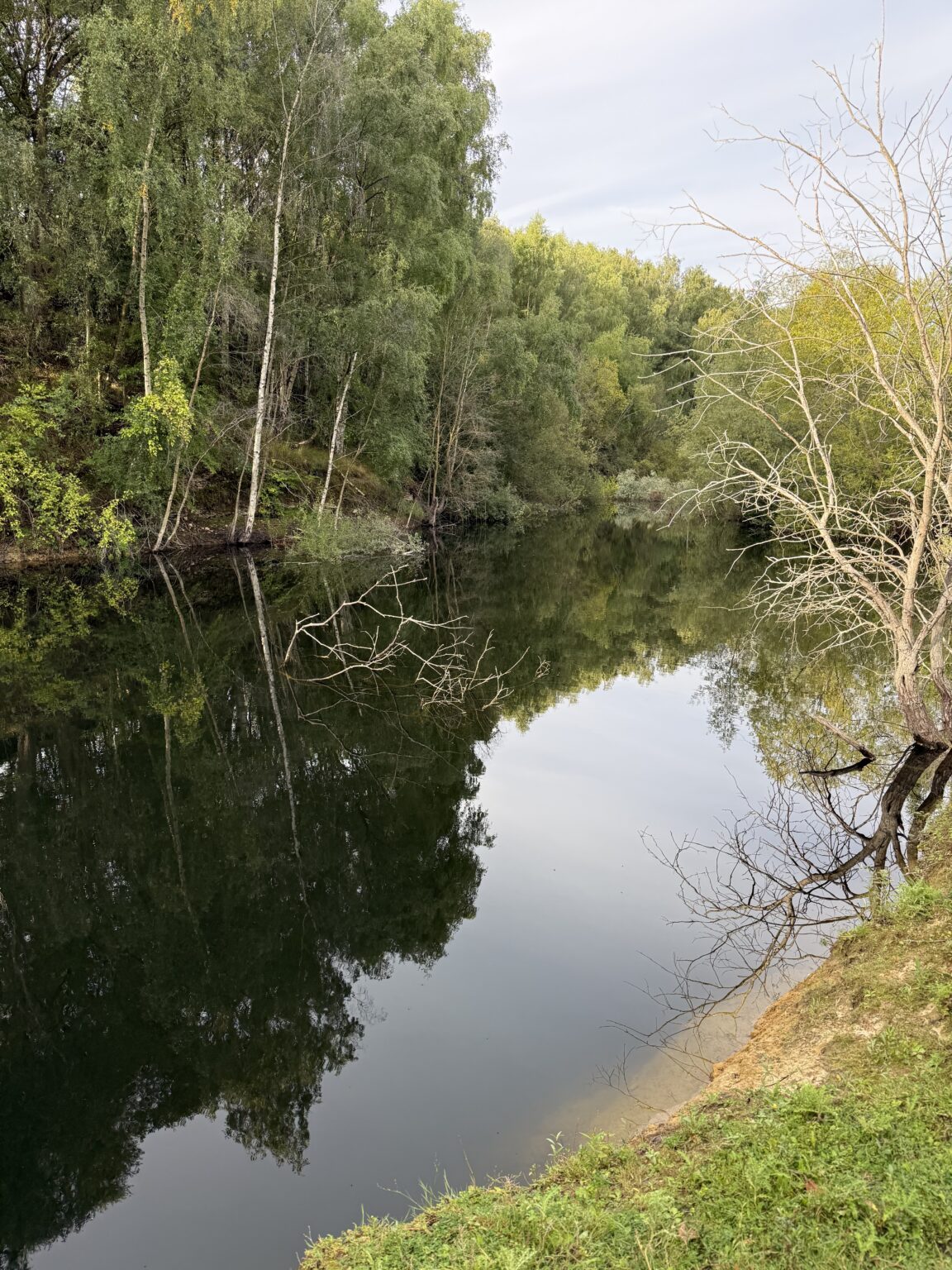 Acorn Lake at Rockingham Forest Park, its wooded banks mirrored in still water