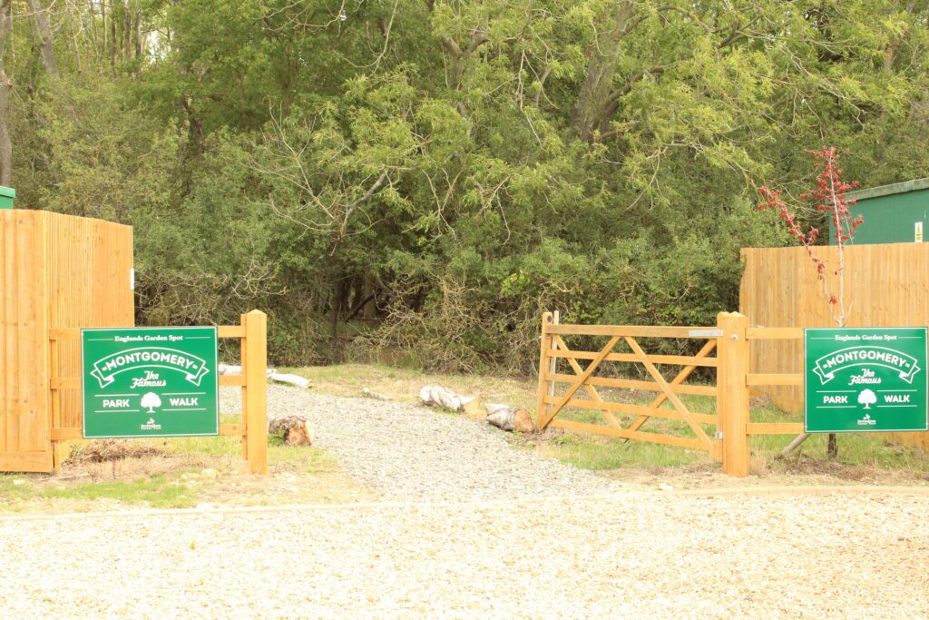 The timber gated entrance to The Famous Montgomery Park Walk, with a green Montgomery sign on each gate and a gravel path leading in