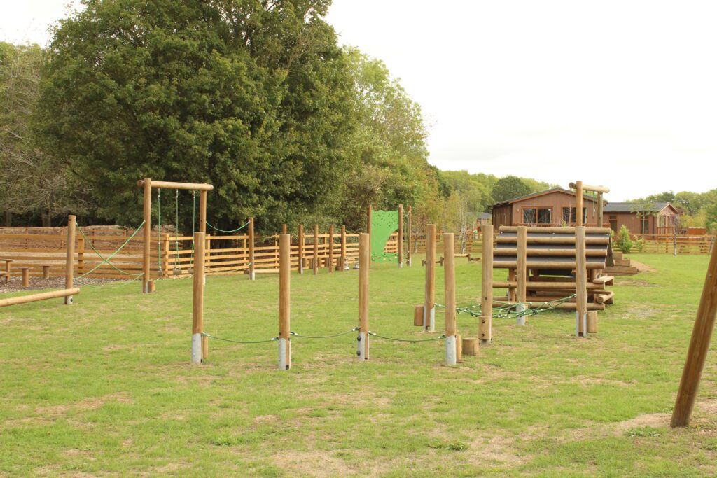 The timber play park at Rockingham Forest Park, with rope bridges and balance beams on mown grass