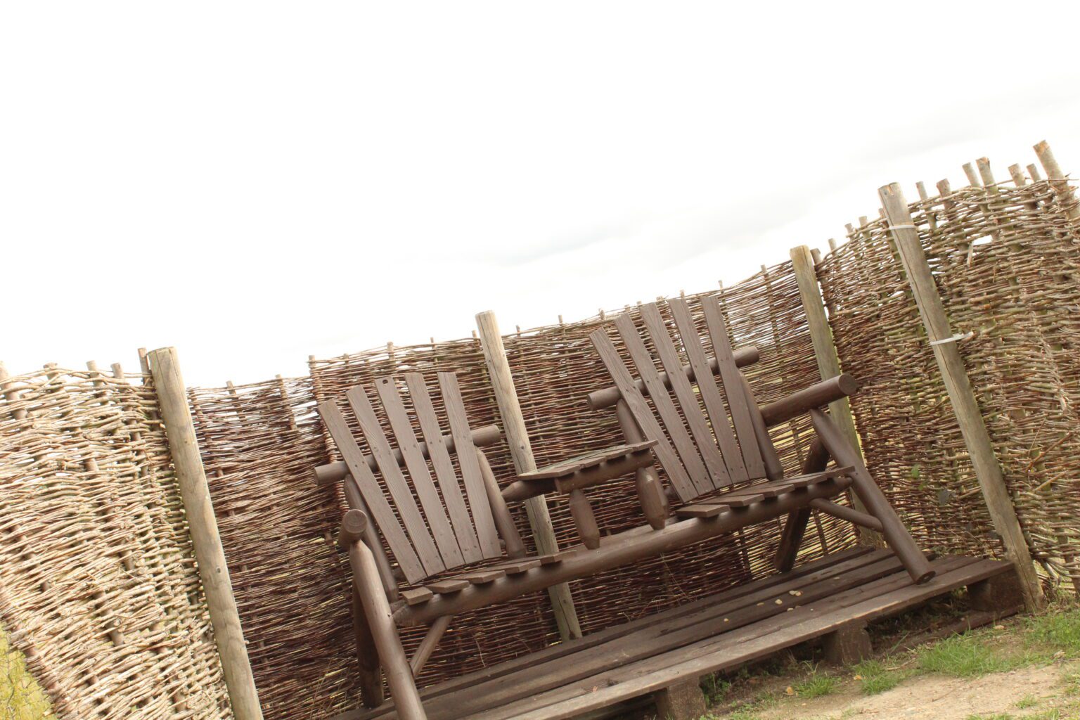 The stargazing spot at Rockingham Forest Park: two rustic timber armchairs with a small table between them, sheltered by woven willow screens