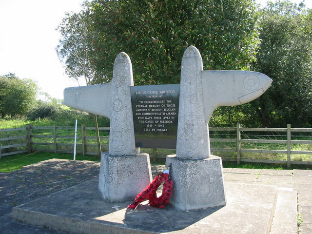 The Kings Cliffe Airfield memorial: two tapering stone plinths topped with fighter wings, an inscribed black stone tablet between them and a poppy wreath at the foot