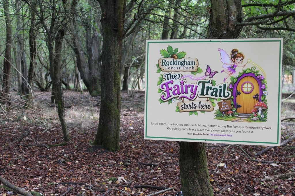 A board in the woodland reading The Fairy Trail starts here, marking the start of the Fairy Fauna Trail at Rockingham Forest Park