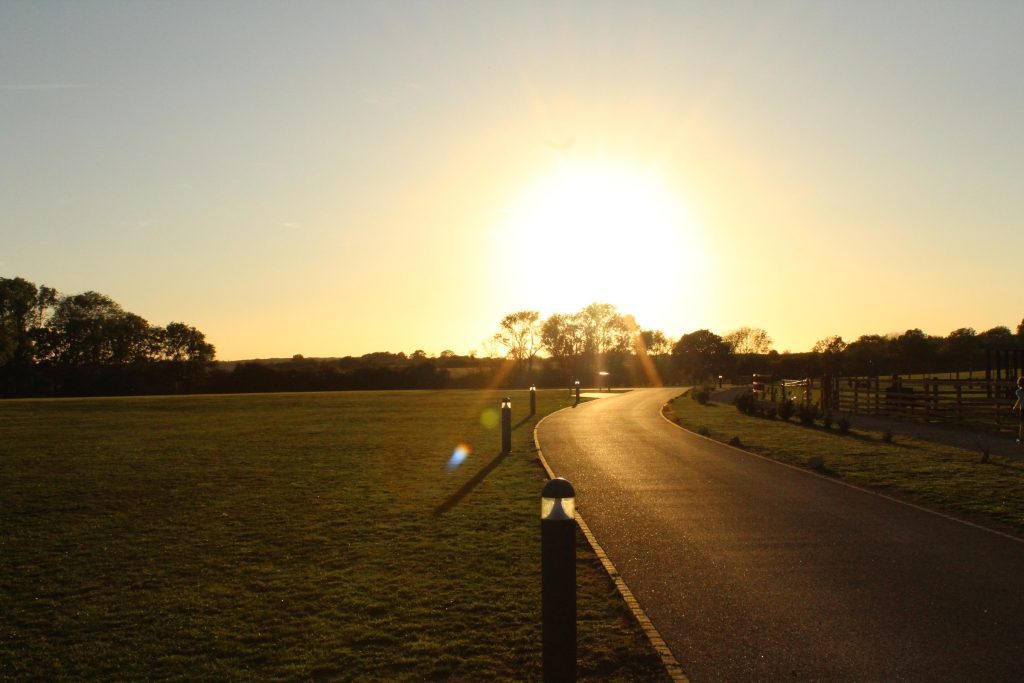 The park at sunset: the sun setting low over open fields beside the entrance drive at Rockingham Forest Park